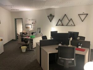 A modern office space featuring multiple desks with computers, decorative wall shelves, and a cozy atmosphere.